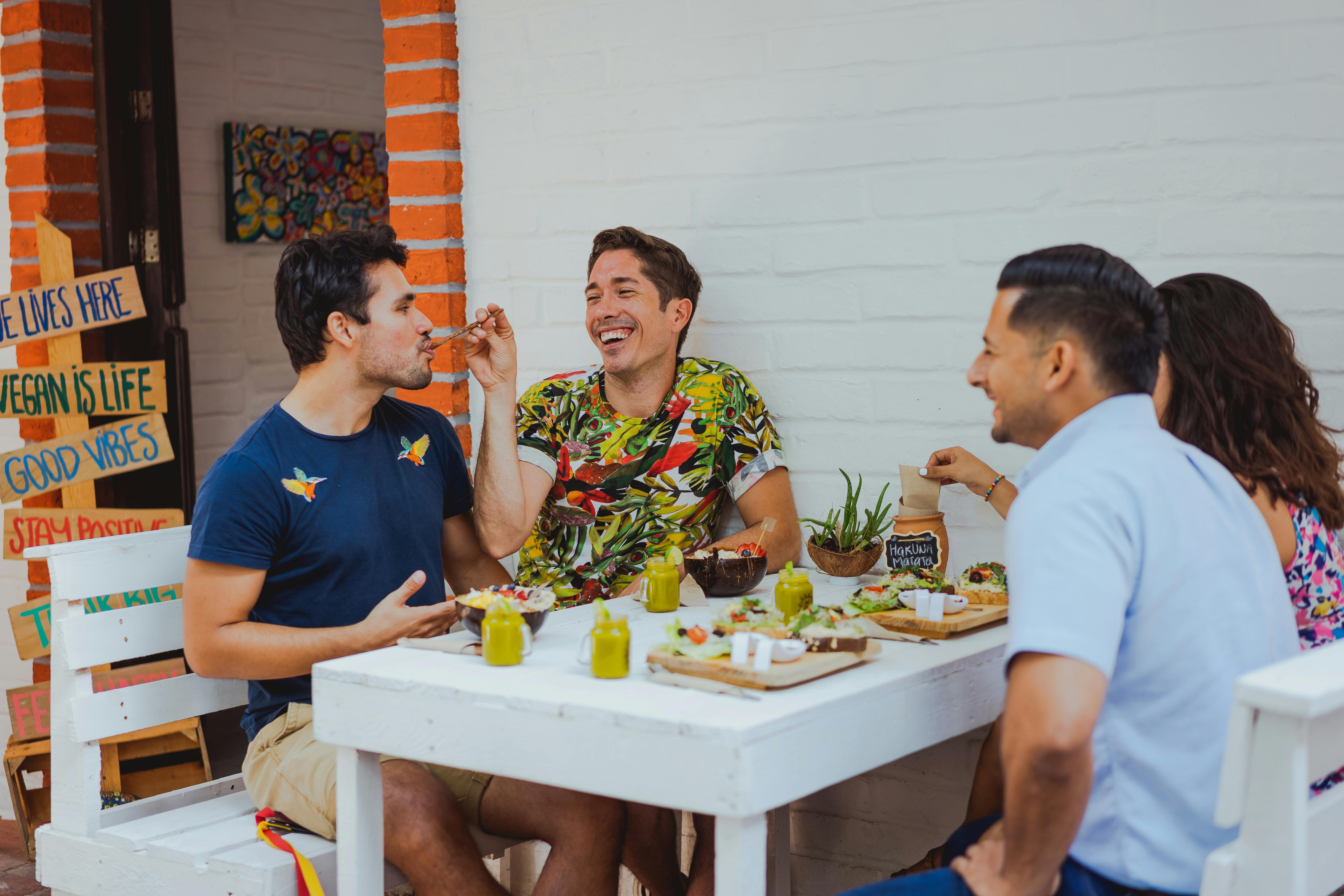 Friends sharing plant-based dishes at an outdoor cafe table